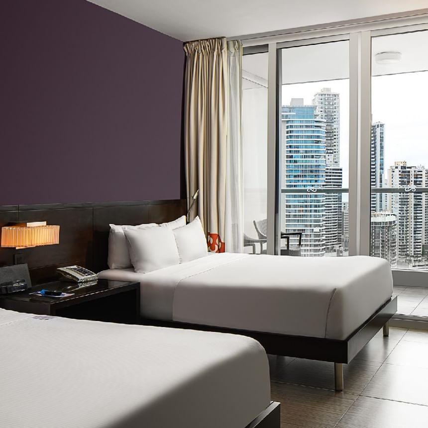 Habitación con dos camas y ventanales de piso a techo con vistas urbanas en Megapolis Hotel Panama