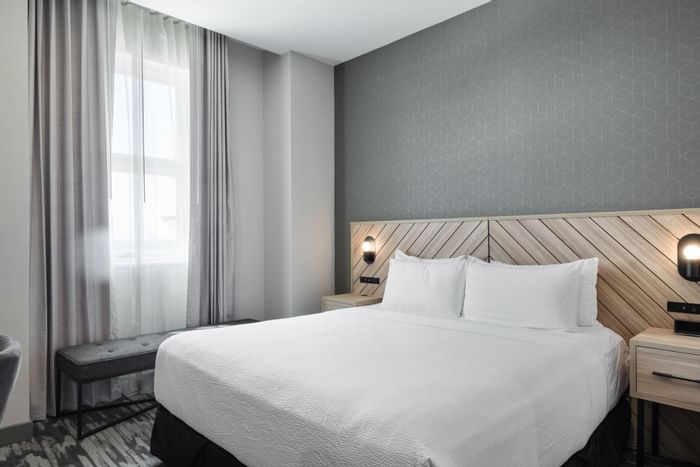 fort worth hotel room with a king sized bed with a wooden headboard in chevron pattern, light grey walls and white ceiling