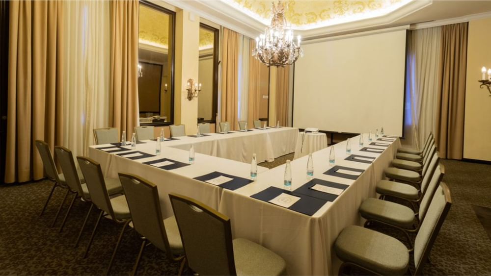 Meeting room with two long tables, chairs, and a chandelier at Quinta Real Monterrey