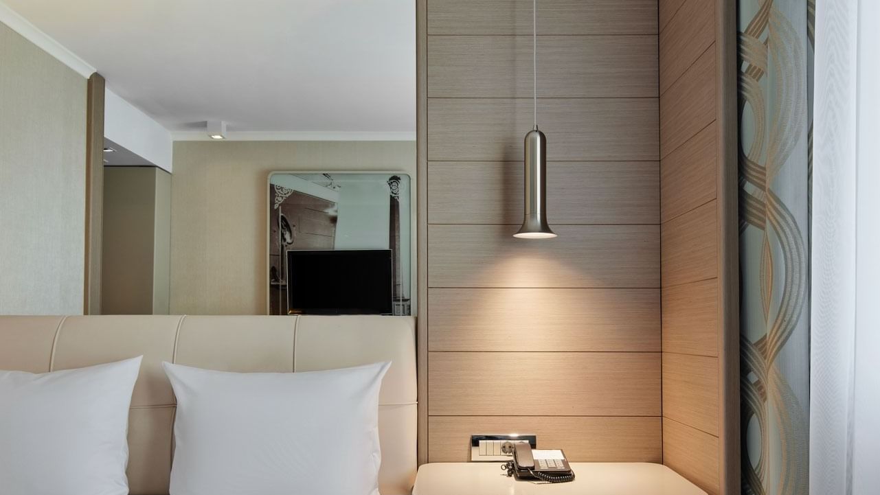 Business Room with a queen bed, pendant light and mirror over a desk at Titanic Comfort Mitte