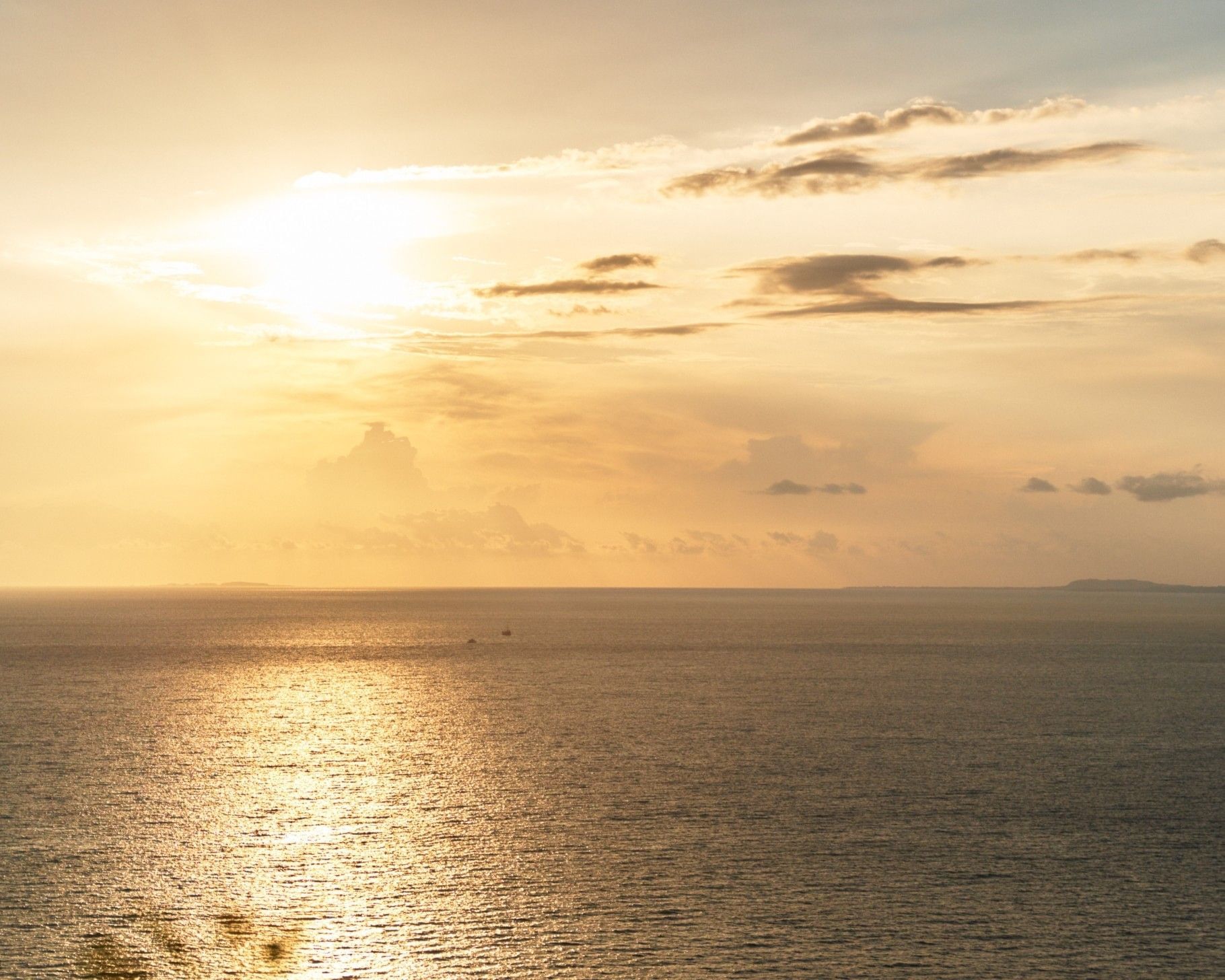 Golden sunset over the Pacific Ocean in Puerto Vallarta with the sun reflecting on the water and soft clouds on the horizon.