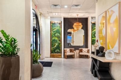 Chic lobby at The Riverwalk Plaza Hotel with modern decor, a lavish chandelier, and an accent wall featuring plant designs