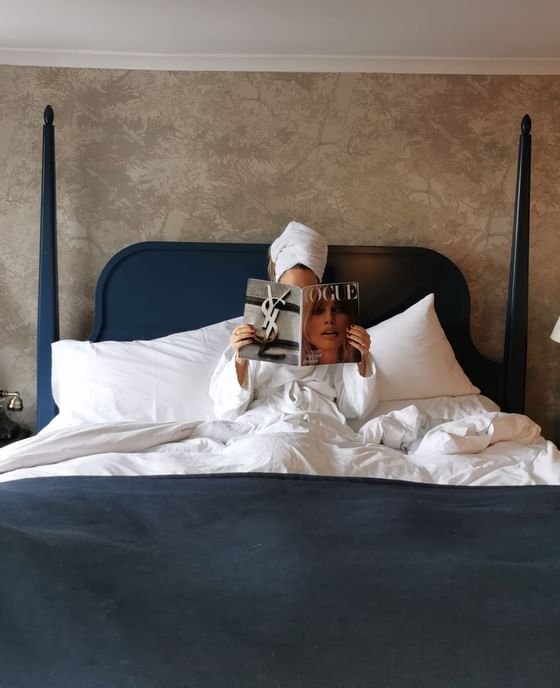 A girl reading a book on a bed at Richmond Hill Hotel