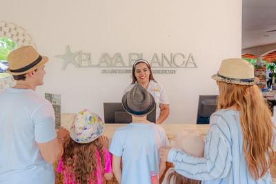 Family checking in at the front desk with smiling staff member at Playa Blanca Beach Resort