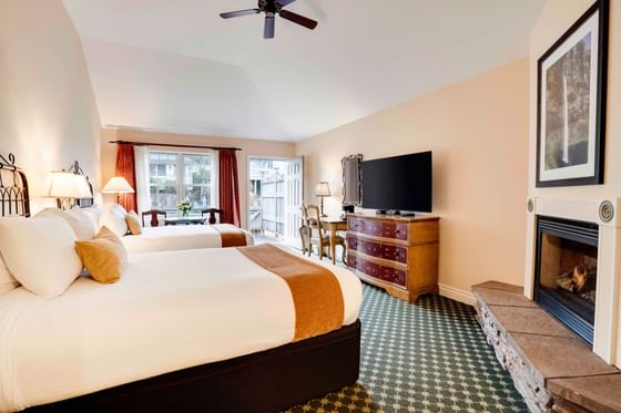 Two queen beds in Two Queen Room by a dresser under a white ceiling with a ceiling fan at Oregon Garden Resort