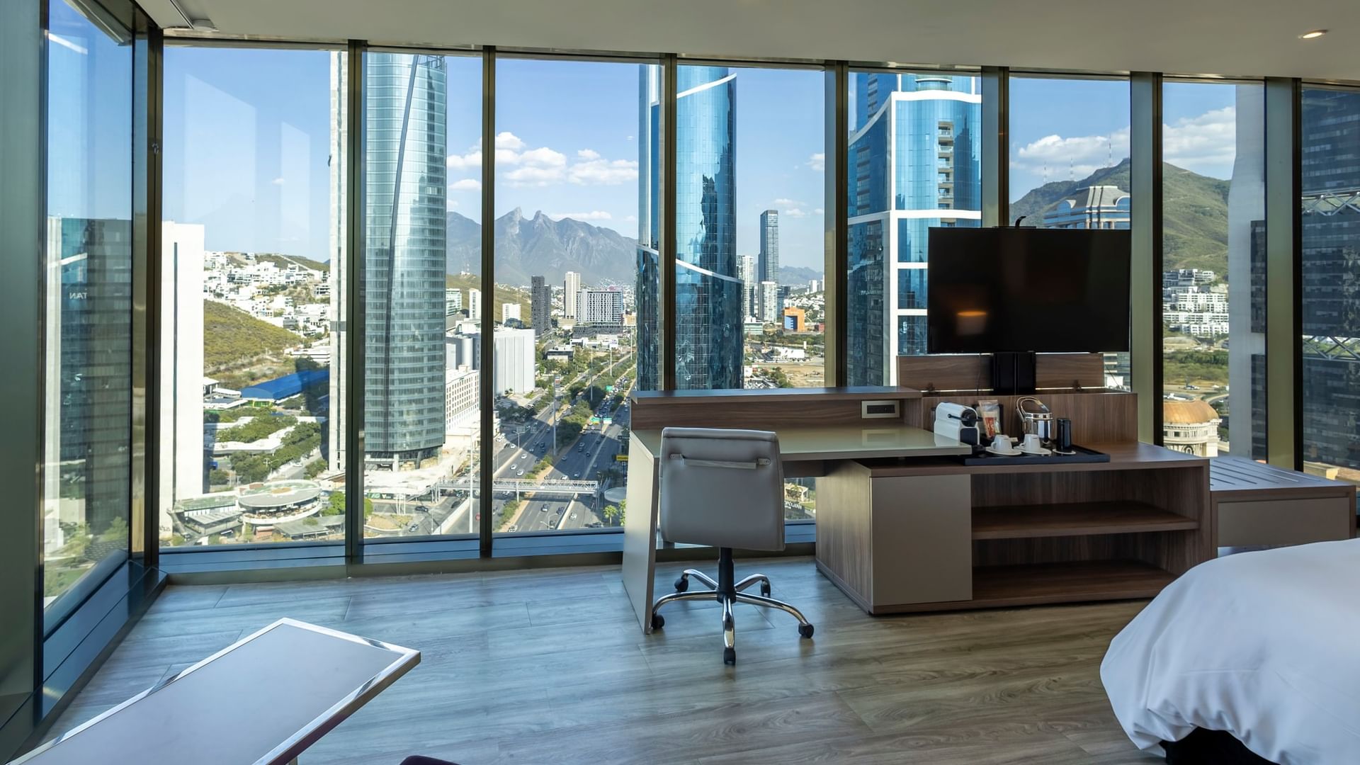 Junior Suite con ventanales amplios, escritorio y vistas panorámicas a la ciudad en Camino Real Fashion Drive Monterrey