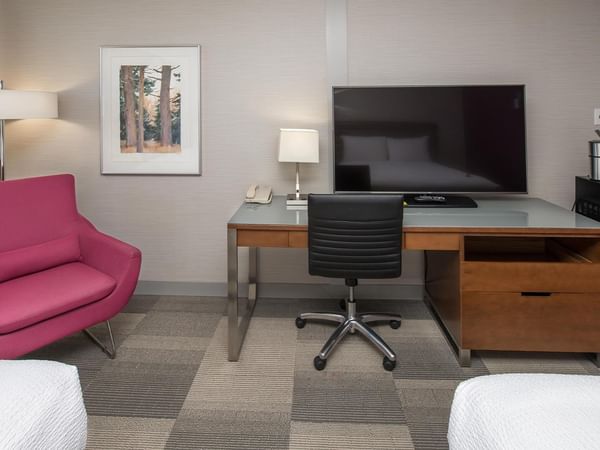Guest room with work desk, pink accent chair, flat-screen TV, and modern amenities at Coast Prince George Hotel