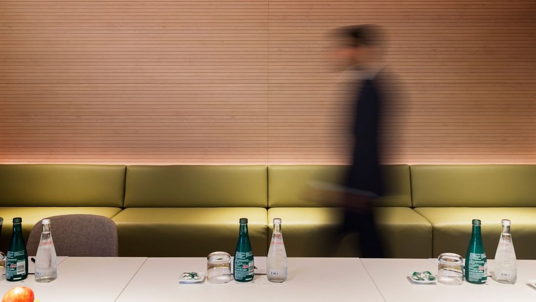 Modern Elara Boardroom setup with refreshments and a blurred figure at Pullman Sydney Olympic Park.