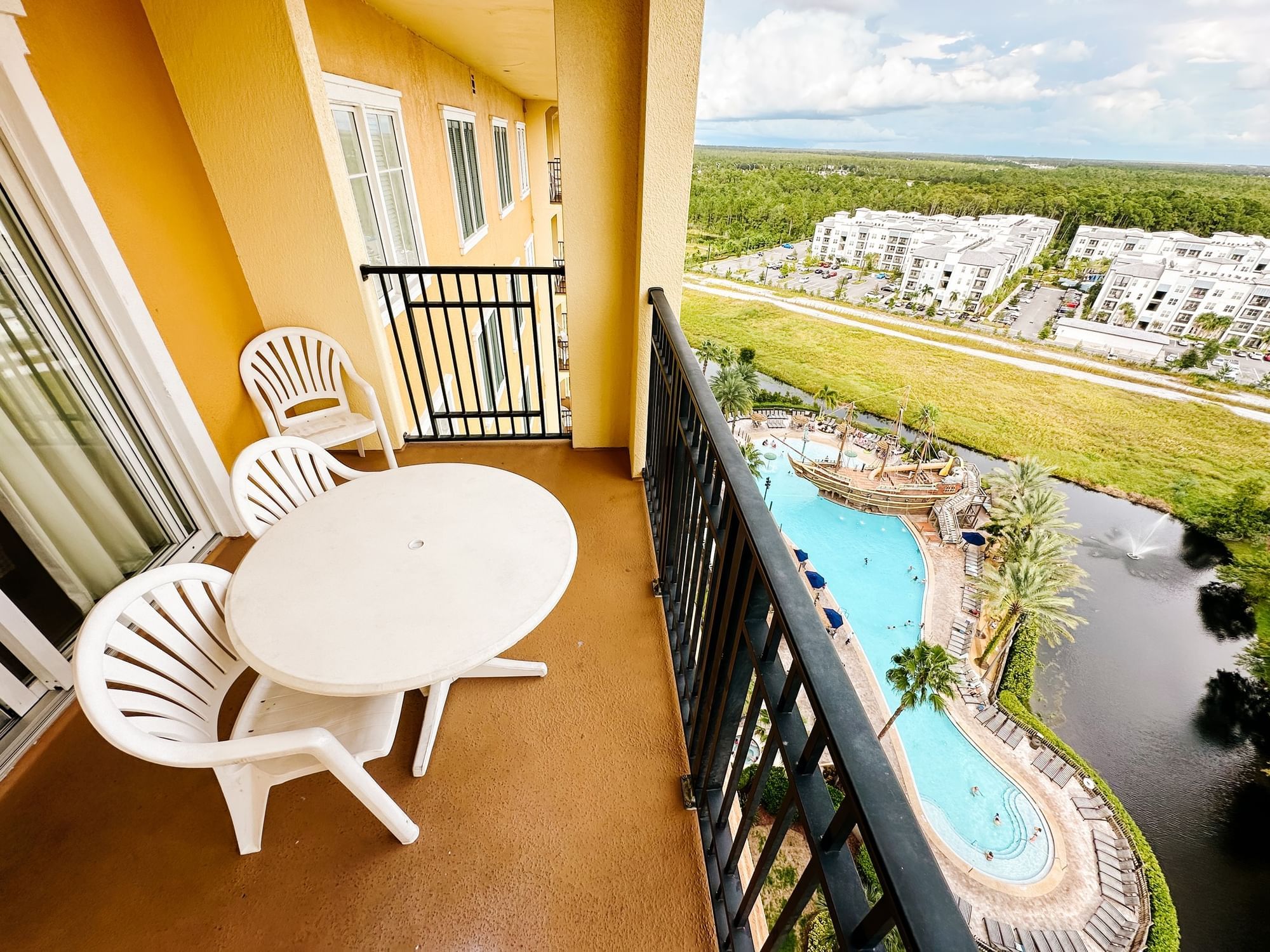 Balcony view with chairs and table overlooking a pool and landscape at Lake Buena Vista Resort Village & Spa