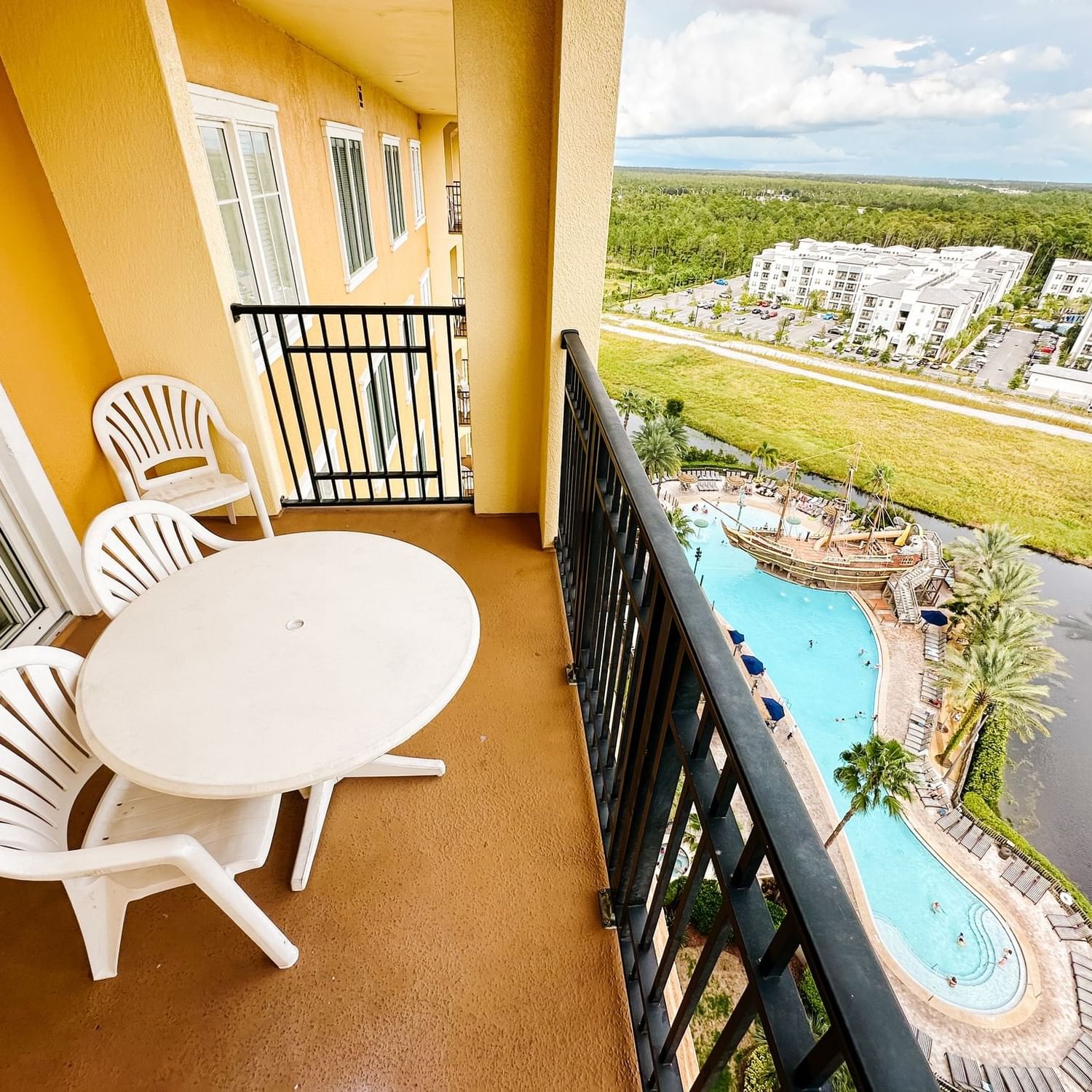 Balcony view with chairs and table overlooking a pool and landscape at Lake Buena Vista Resort Village & Spa
