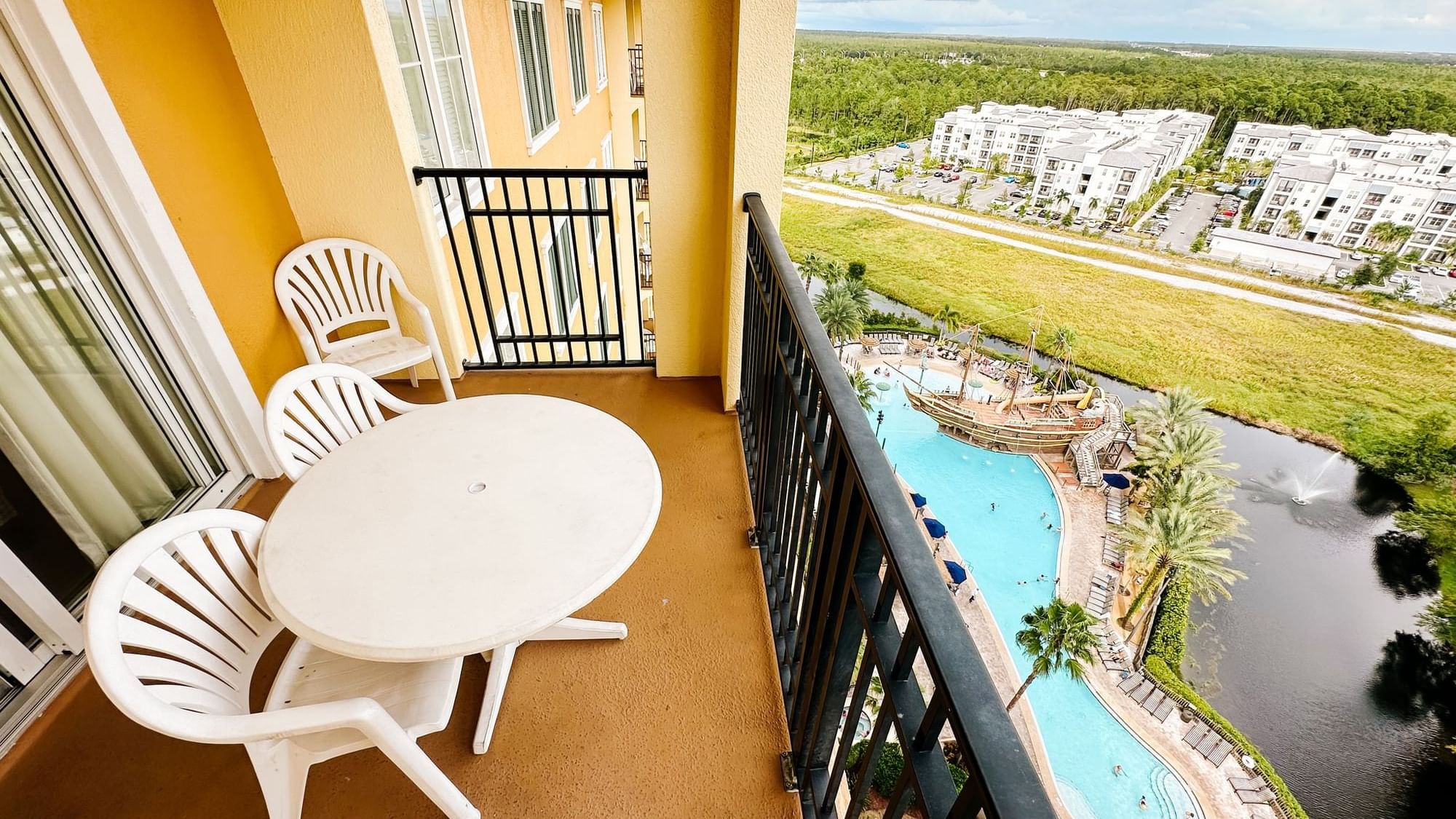 Balcony view with chairs and table overlooking a pool and landscape at Lake Buena Vista Resort Village & Spa