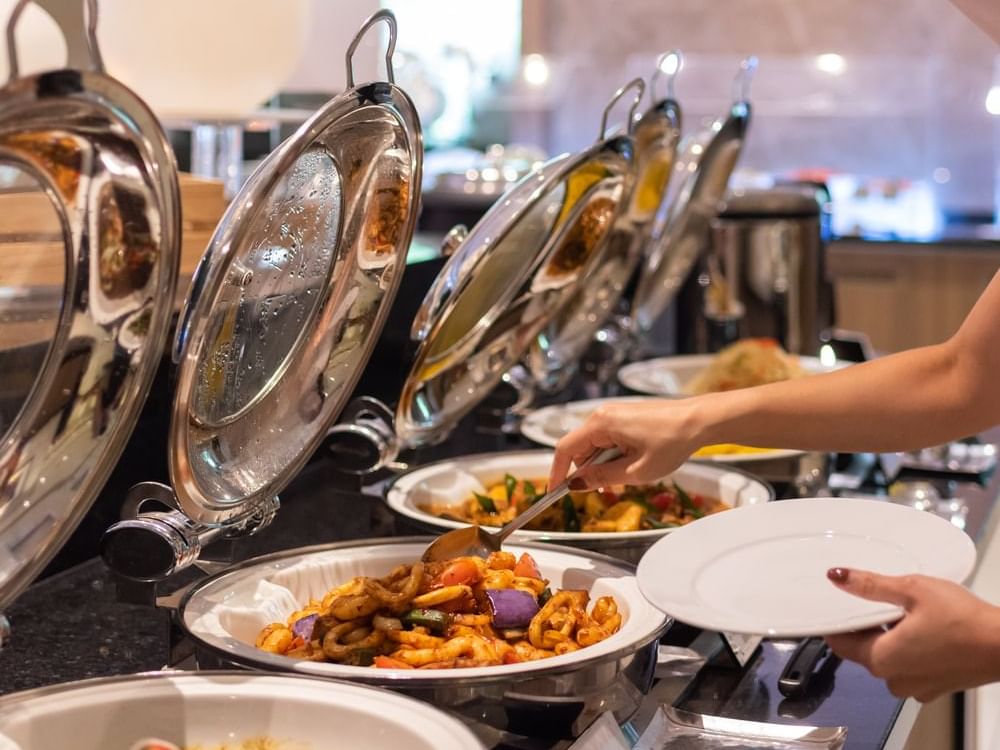 People serving from a buffet in Café Mosaic at Carlton Hotel Singapore