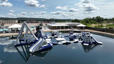 Aqua Park with various climbing structures and slides, surrounded by lush greenery and clouds near Off Shore Resort