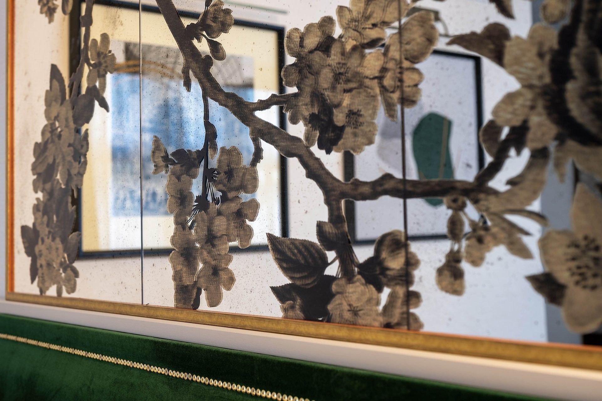 Floral pattern on a mirror above a green velvet headboard with gold trim at The Capital Hotel, Apartments and Townhouse