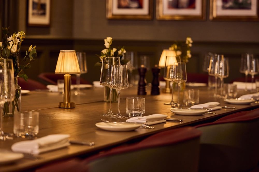 Elegant dining table set with glassware, white plates, and table lamps in warm lighting at The Bedford Hotel Belfast