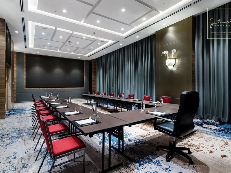 Modern U-typed boardroom with red chairs, and a large black screen on the wall at Sunway Hotel Big Box