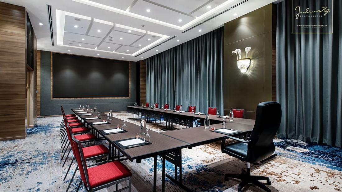 Modern U-typed boardroom with red chairs, and a large black screen on the wall at Sunway Hotel Big Box