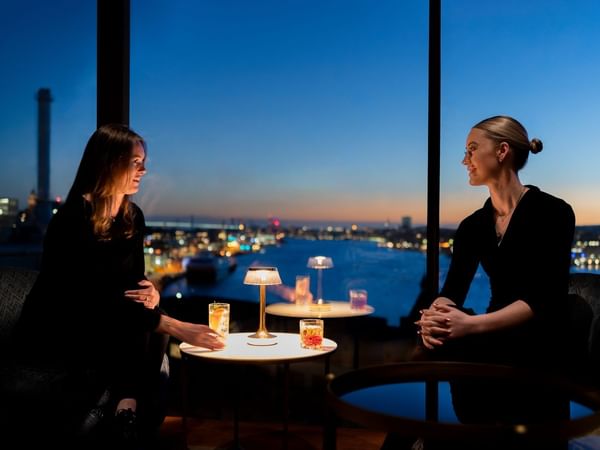 Två kvinnor som njuter av cocktails med utsikt över Göteborg från View Skybar & Restaurant på Hotel Riverton