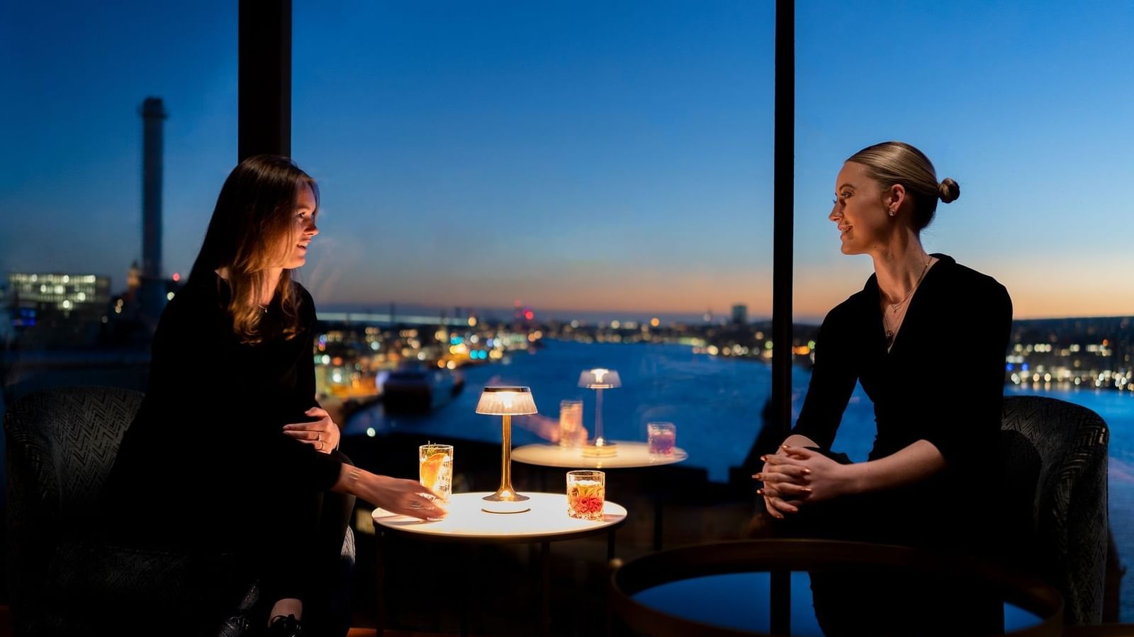 Två kvinnor som njuter av cocktails med utsikt över Göteborg från View Skybar & Restaurant på Hotel Riverton