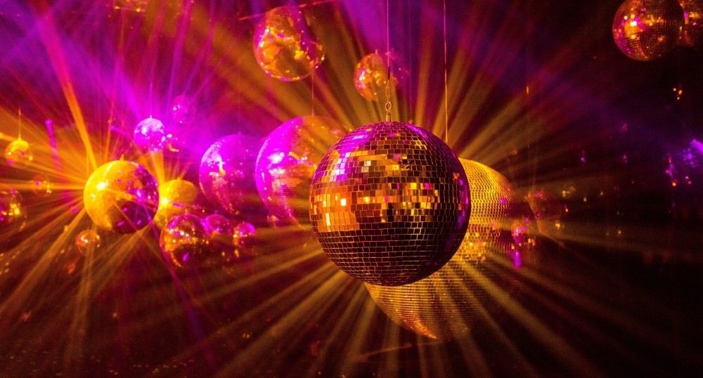 Streaks of orange and bright pink light bounce off of a dozen hanging disco balls representing nightlife in Orlando.