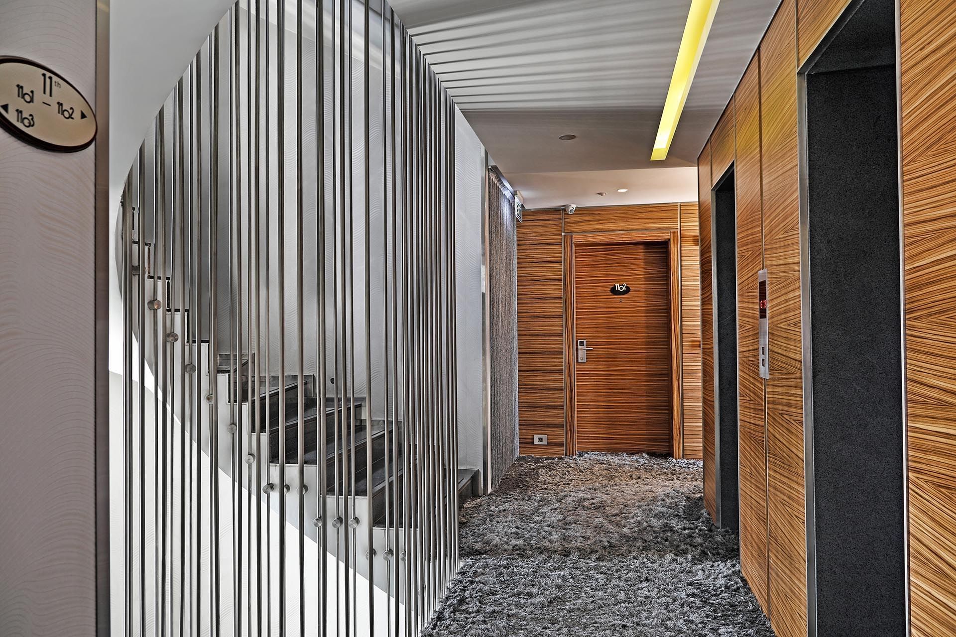 Wooden elevator doors by a metal rod partition under a bright ceiling light at Warwick Stone 55 - Beirut