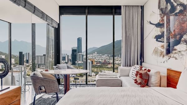 Comfy bed and living area with city view of Deluxe Room at FA Hotels & Resorts