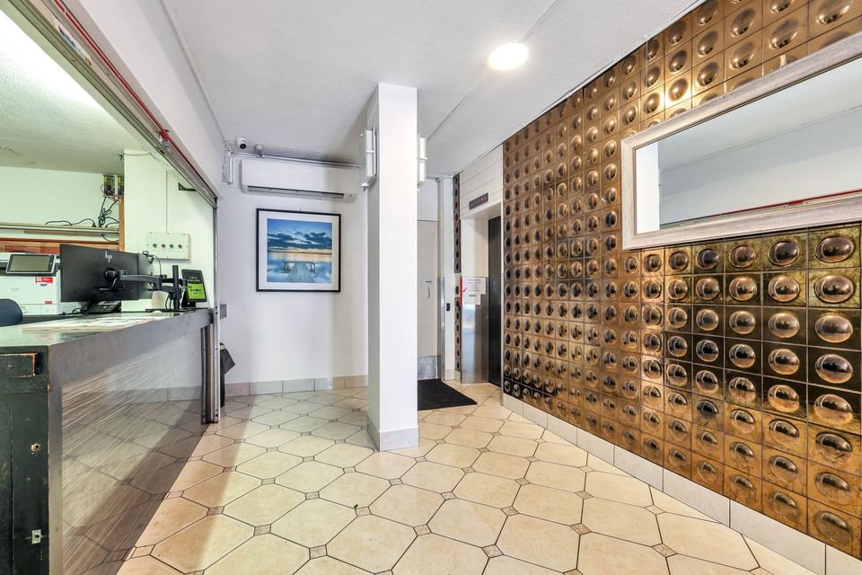 Lobby with a counter and decorative bronze wall at Darwin Poinciana Inn in Mitchell St