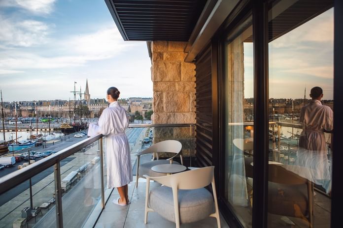 Lady overlooking the city wearing a bathrobe from the balcony lounge area at Oceania Hotels