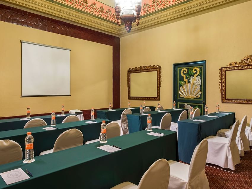 Salón Virreinal with green table linens and a projector screen at Quinta Real Aguascalientes