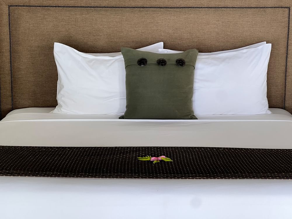Bed with white linens and green pillow in Shefa Pool Villa at Warwick Le Lagon Vanuatu Efate.