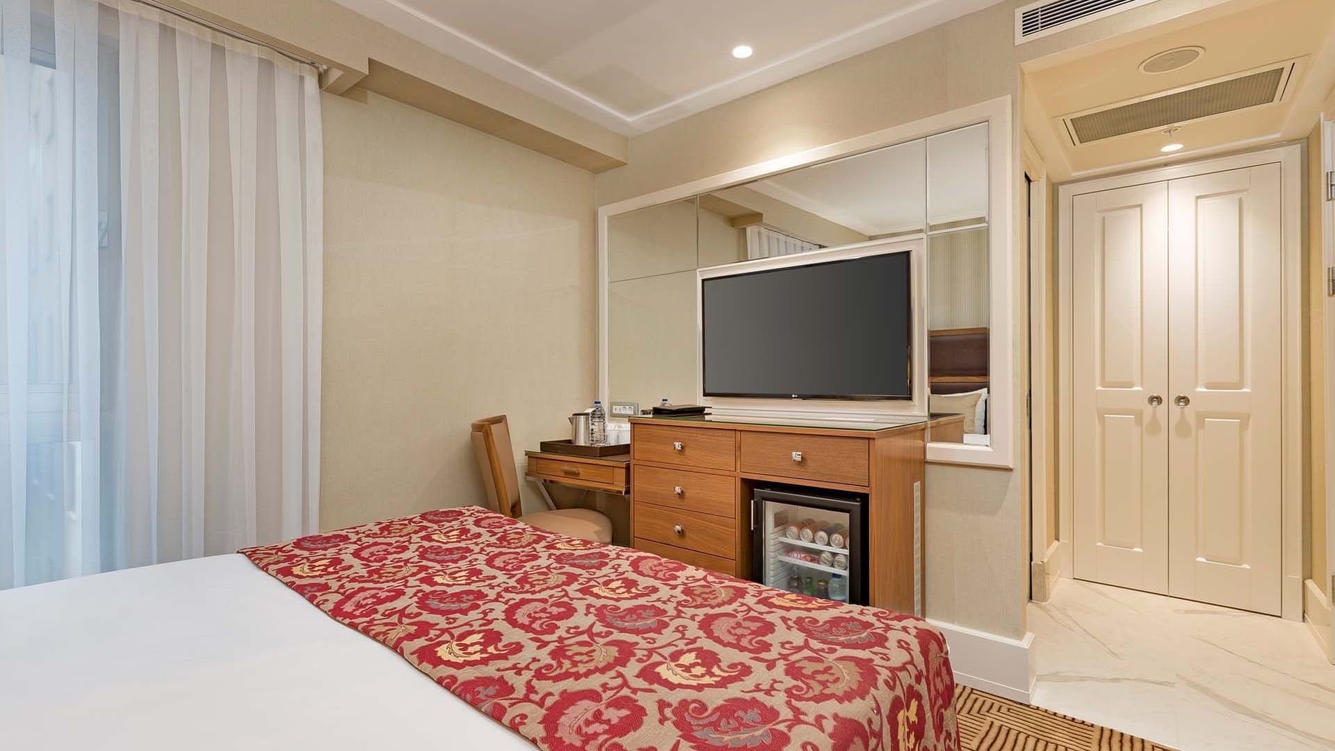 Titanic City Taksim’deki Superior odada konforlu bir king-size yatak ve televizyon.