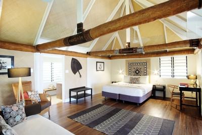 Beachfront Bures room with exposed beams, hardwood floors, and traditional furnishings at Musket Cove Island Resort & Marina