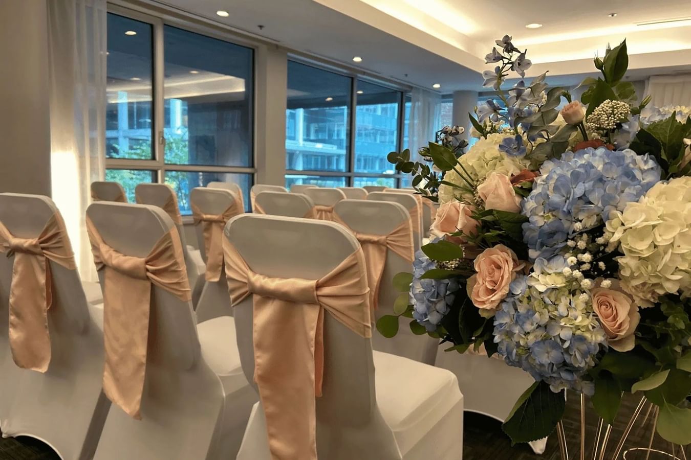 Rows of white chairs with peach silk bows and floral bouquets at Warwick Le Crystal Montreal