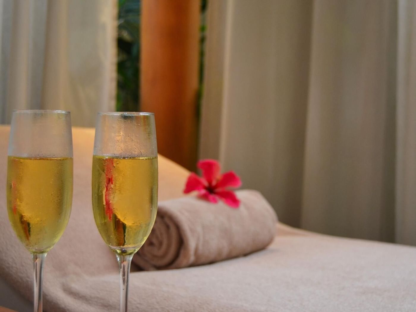 2 Champagne glasses by a spa bed at FA Hotels & Resorts