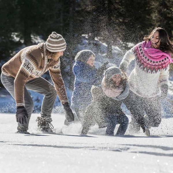 A family playing on the snow at Falkensteiner Hotels