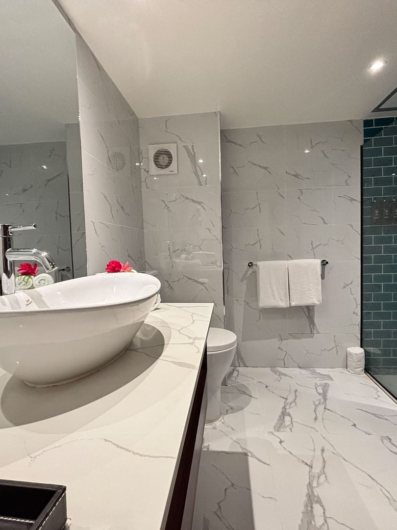 Elegant bathroom with white sink, glass shower, and marble floors in a Superior Garden View Room at Warwick Fiji Resort and Spa.