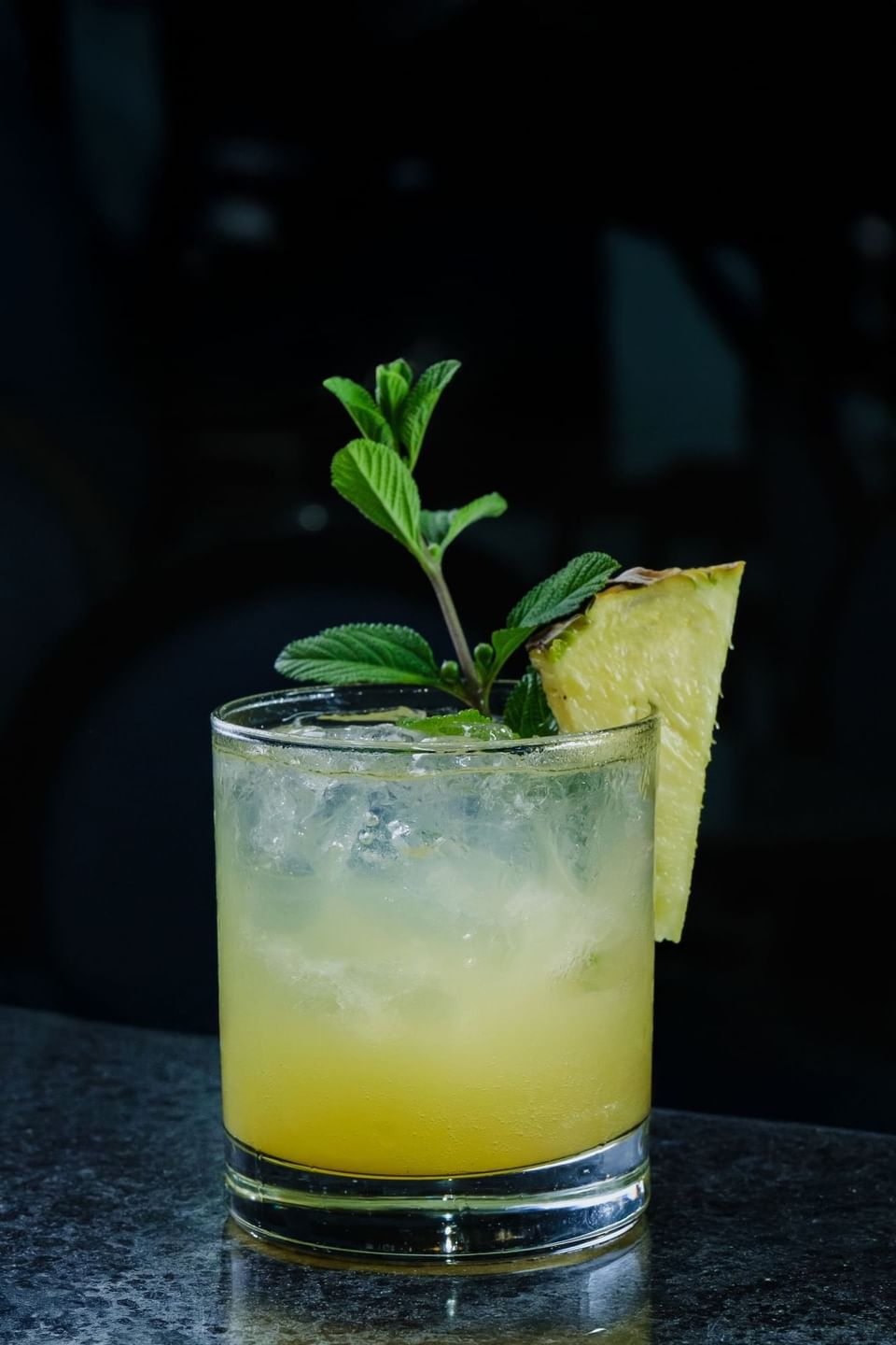 Close-up of Iced cocktail with pineapple wedge and mint garnish in a glass at Las Olas Restaurants