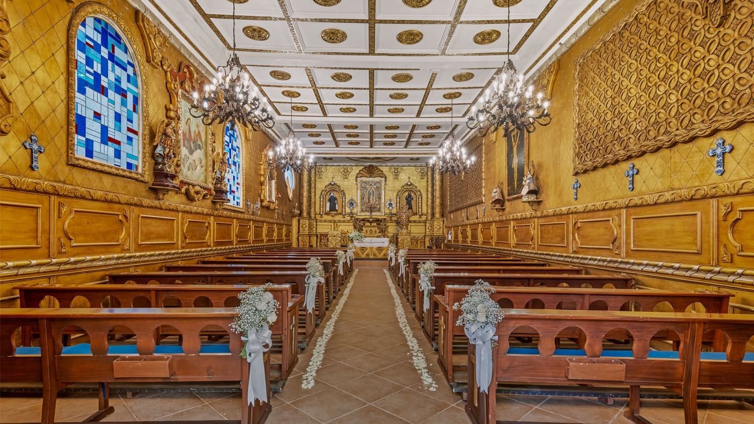 Beautifully decorated church or chapel near Fiesta Americana, with golden walls, ornate chandeliers, and pews