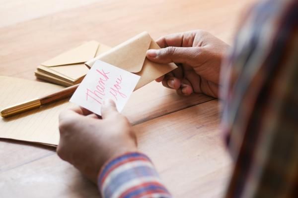 Bride to be writing handwritten thank you notes to guests instead of wedding favour, a great way to save money