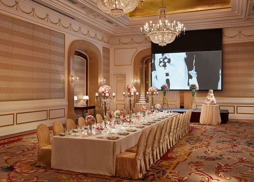 Wedding reception featuring a long table adorned with floral centerpieces, chandeliers, and screen at Park Hyatt Saigon