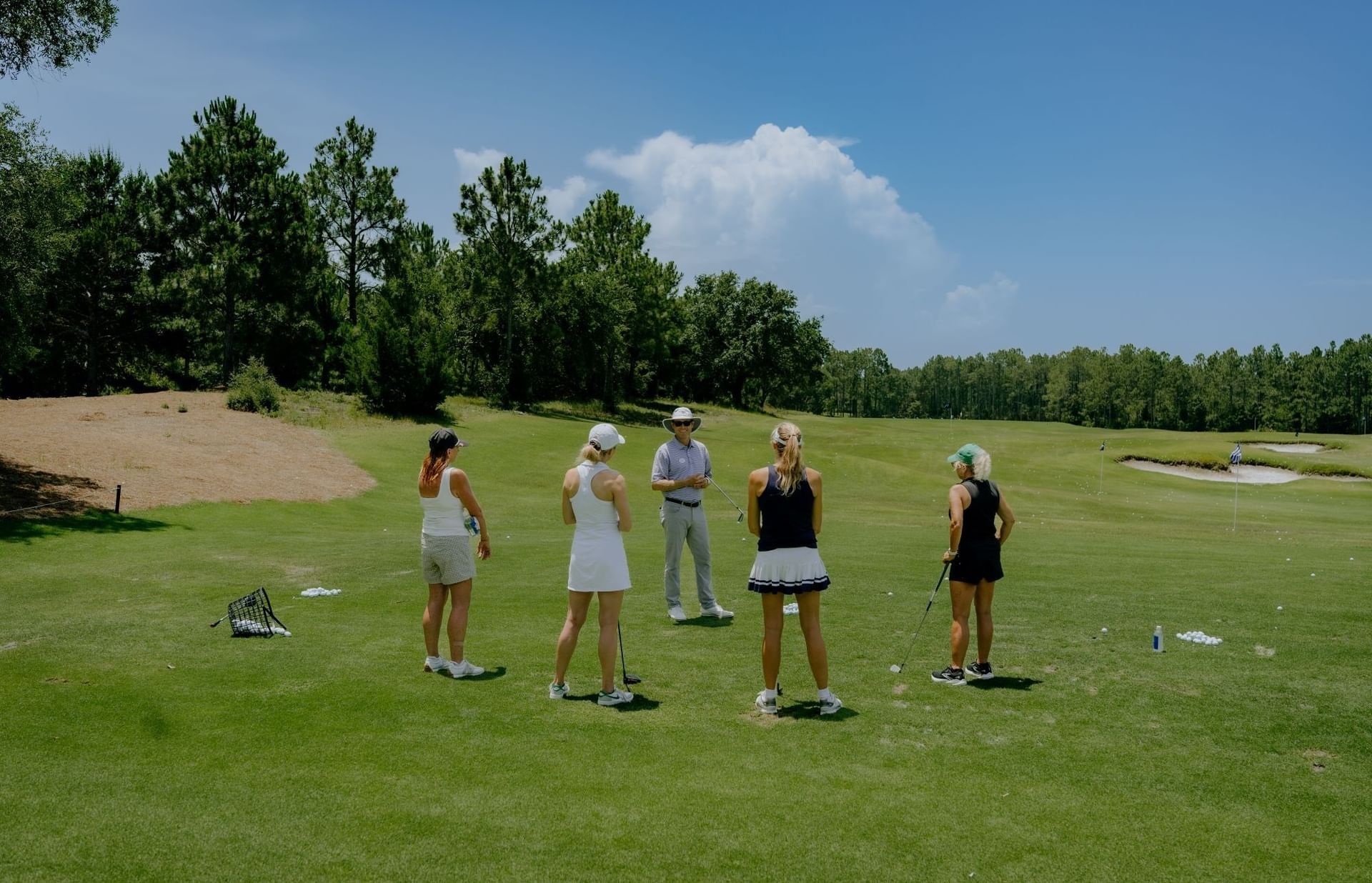 Group of women practicing golf with instructor on Camp Creek Inn's golf course