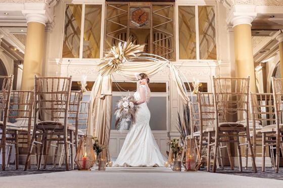 A bride posing at the wedding arch at The Met Hotel Leeds