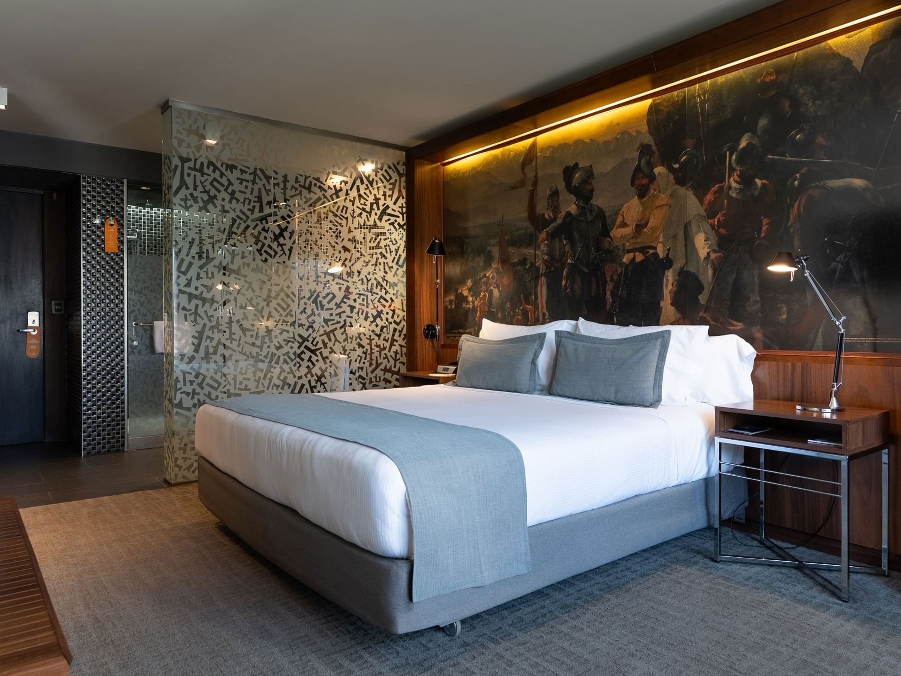 Quarto Duplo Standard com cama king, arte mural e banheiro com parede texturizada no Cumbres Lastarria, Santiago.