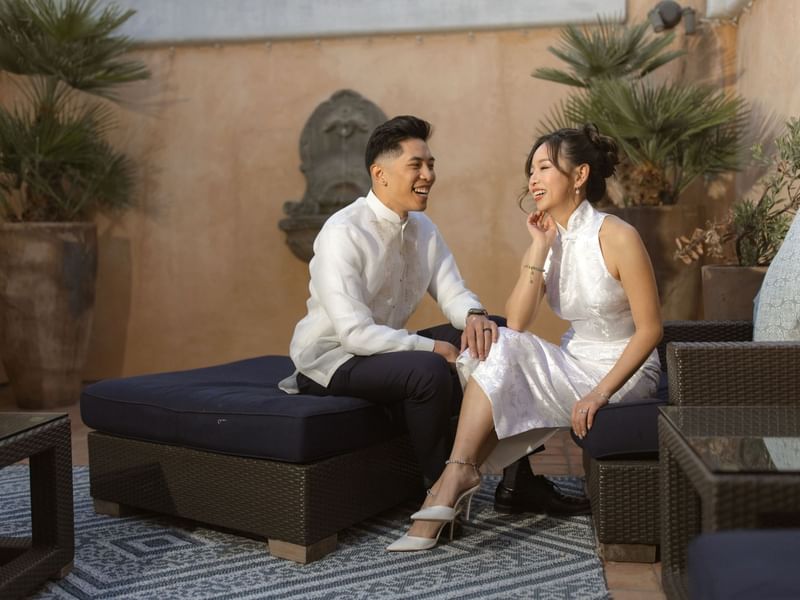 A joyful couple enjoying the Minimoon Package at El Prado Hotel, relaxing on an outdoor patio