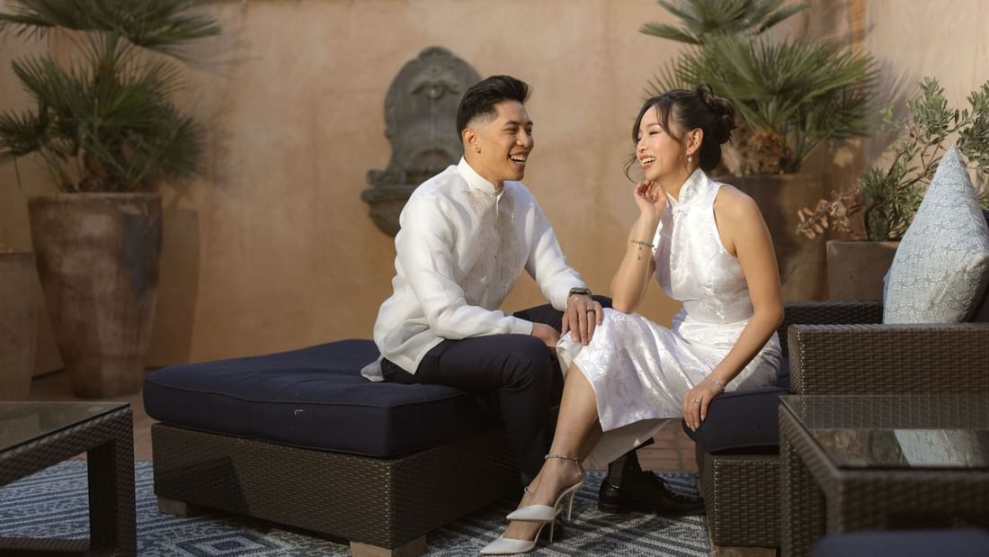 A joyful couple enjoying the Minimoon Package at El Prado Hotel, relaxing on an outdoor patio