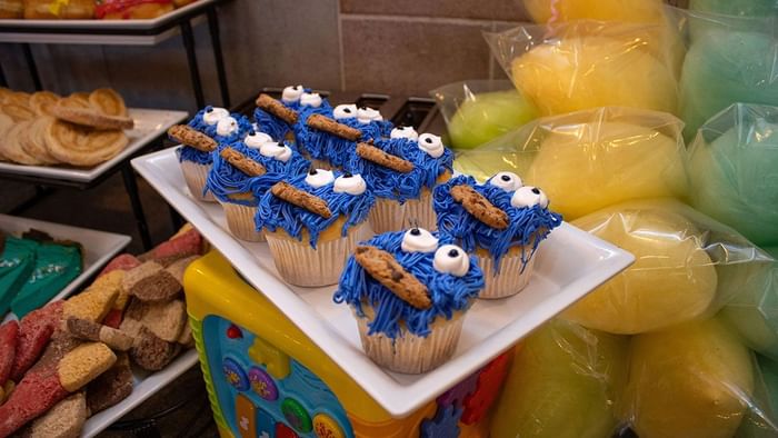 Blue-frosted cupcakes with cookies and candy eyes on a tray with cotton candy in Palmira Cafeteria at Araiza Calafia