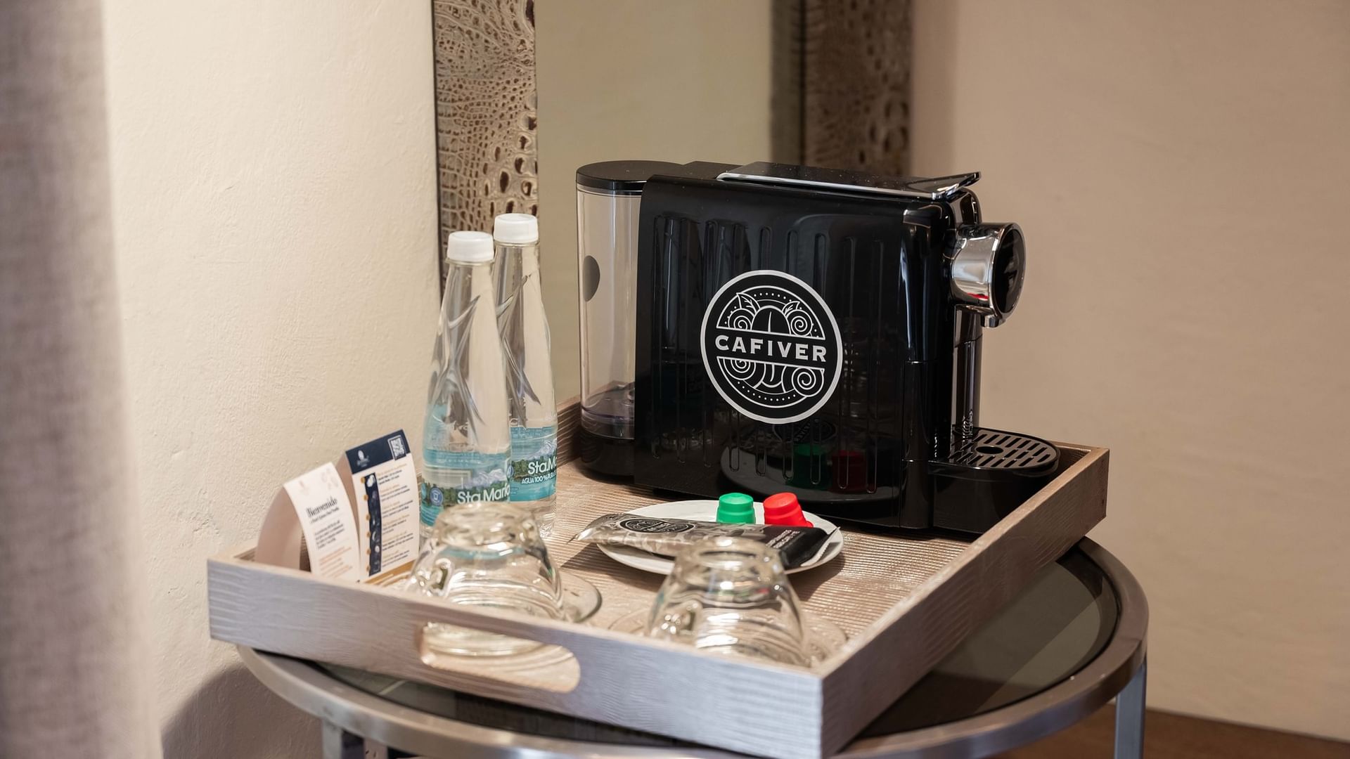 Bandeja con cafetera, botellas de agua y vasos en habitación De Lujo King de Quinta Real Puebla en Heroica Puebla de Zaragoza