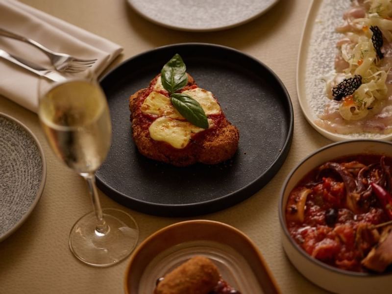 Dining table with assorted dishes and a glass in Modo Mio at Crown Promenade Perth