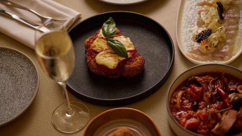 Dining table with assorted dishes and a glass in Modo Mio at Crown Promenade Perth