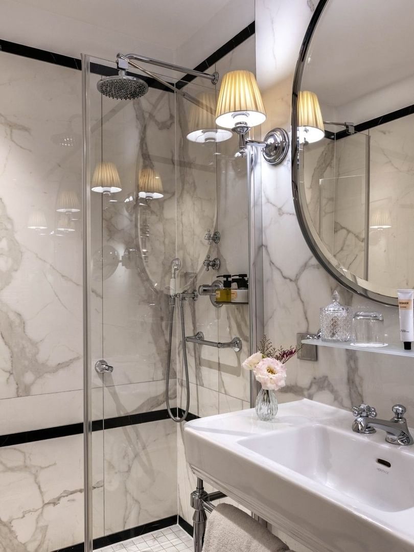 Superior Single Room bathroom featuring a marble vanity with mirror by the glass shower at HHotel Westminster Paris